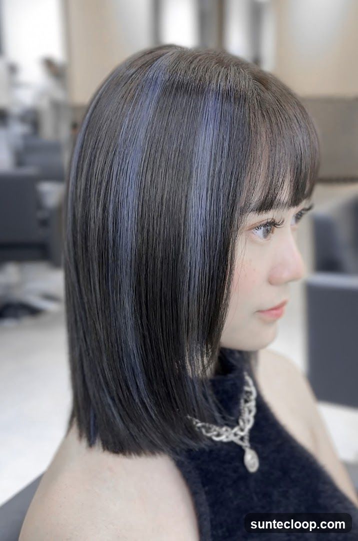 Woman with dark bob haircut and subtle blue highlights