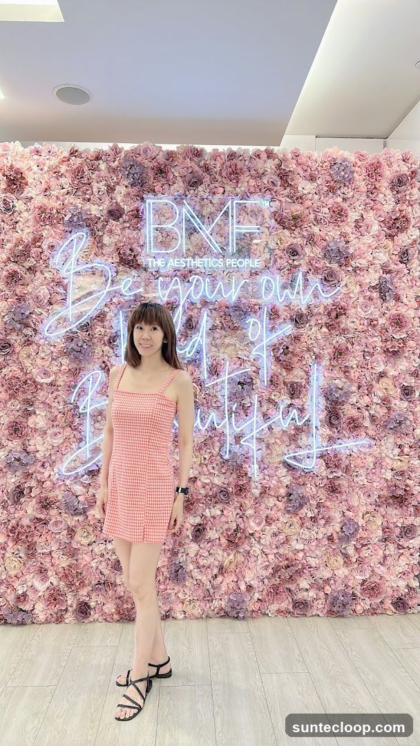 Woman Poses in Front of Floral Wall with Neon Sign
