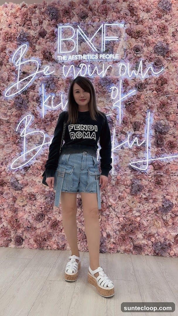 Woman Poses in Front of Floral Wall with Neon Sign