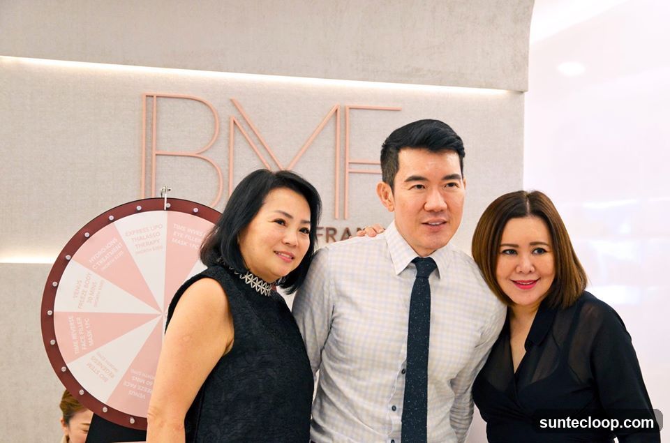Three people posing in front of a salon logo