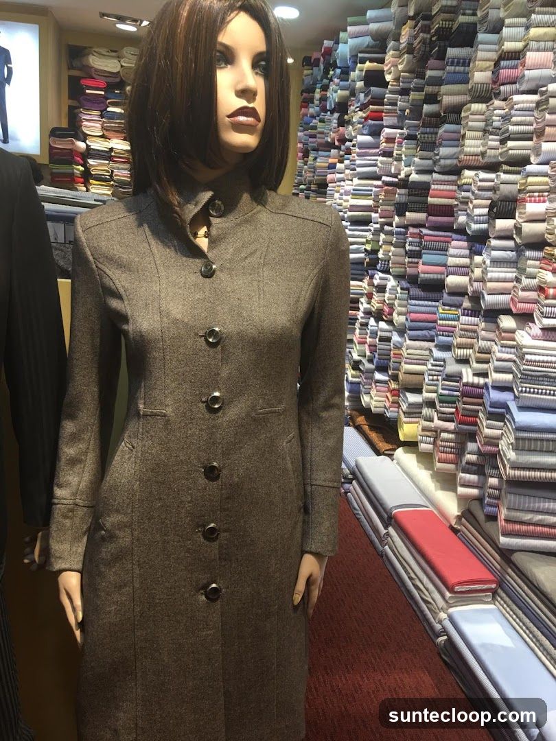Mannequin in a coat surrounded by fabric rolls