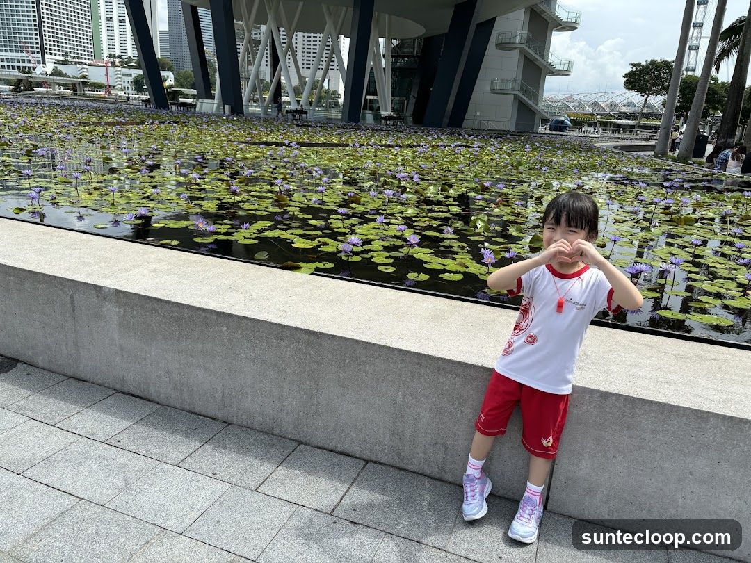 Child making heart shape with hands in front of water lilies