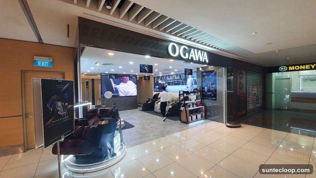 The exterior of an OGAWA store, featuring massage chairs and promotional displays. The store's name is prominently displayed above the entrance. To the right, a money exchange service is visible.