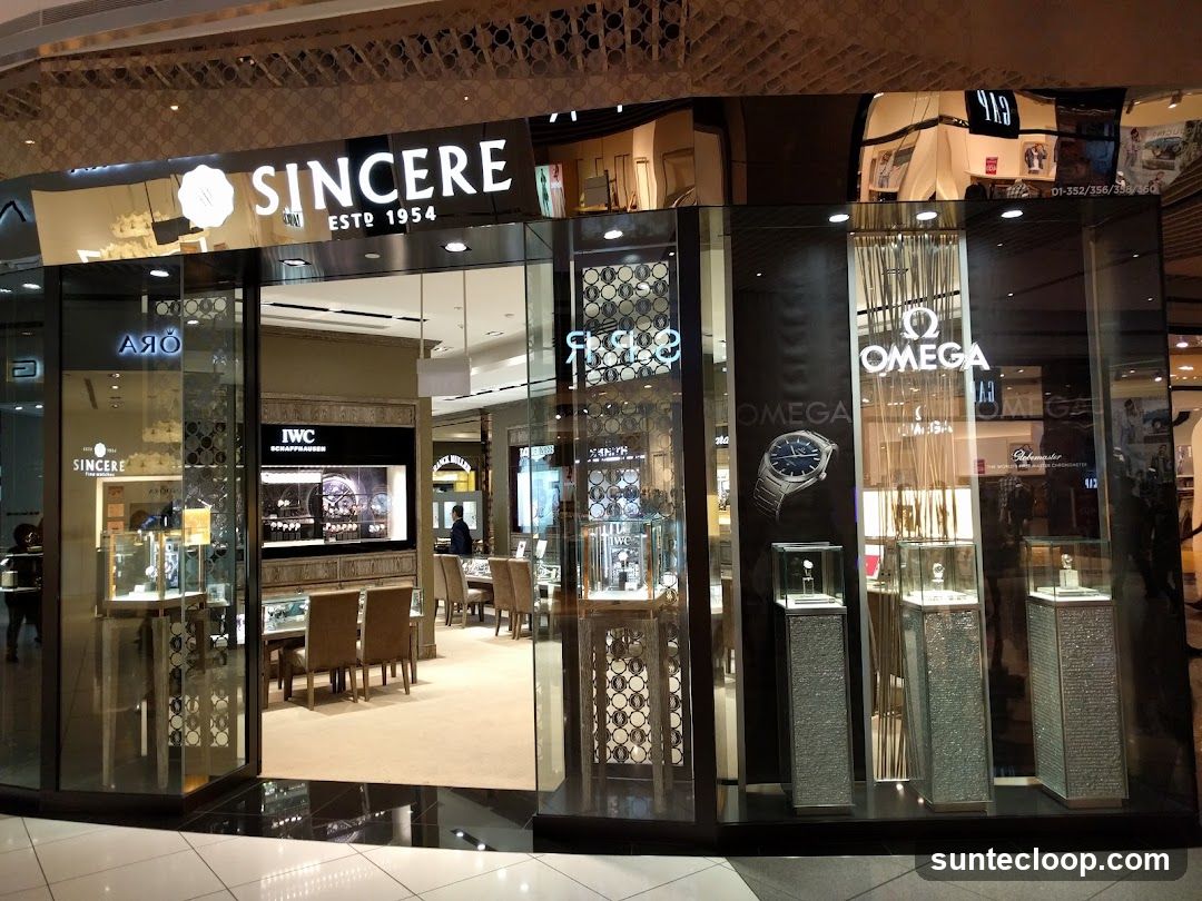 The exterior of a Sincere watch store, featuring prominent signage for Sincere, Omega, and IWC. The store has large glass windows displaying watches in illuminated cases and a seating area inside.
