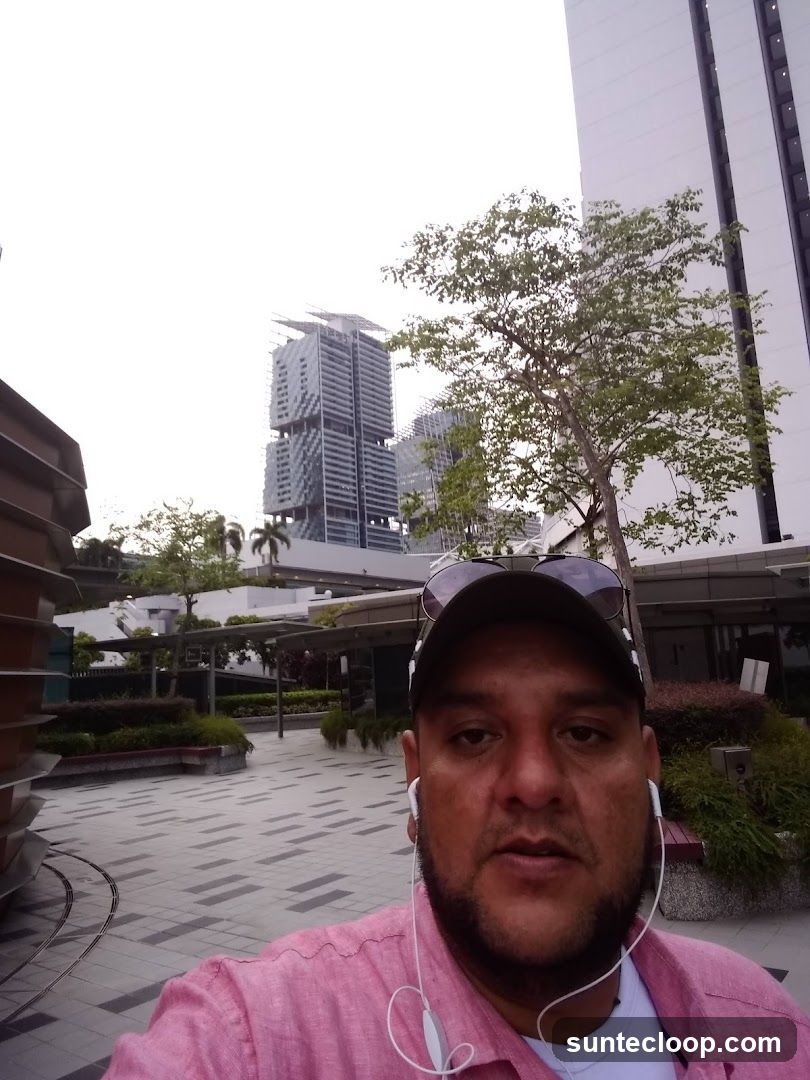 Man in a pink shirt taking a selfie outdoors